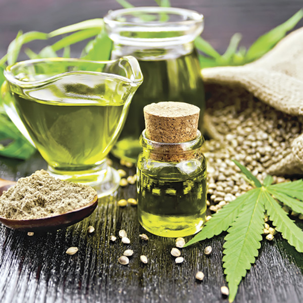 Oil hemp in two jars and sauceboat on wooden board